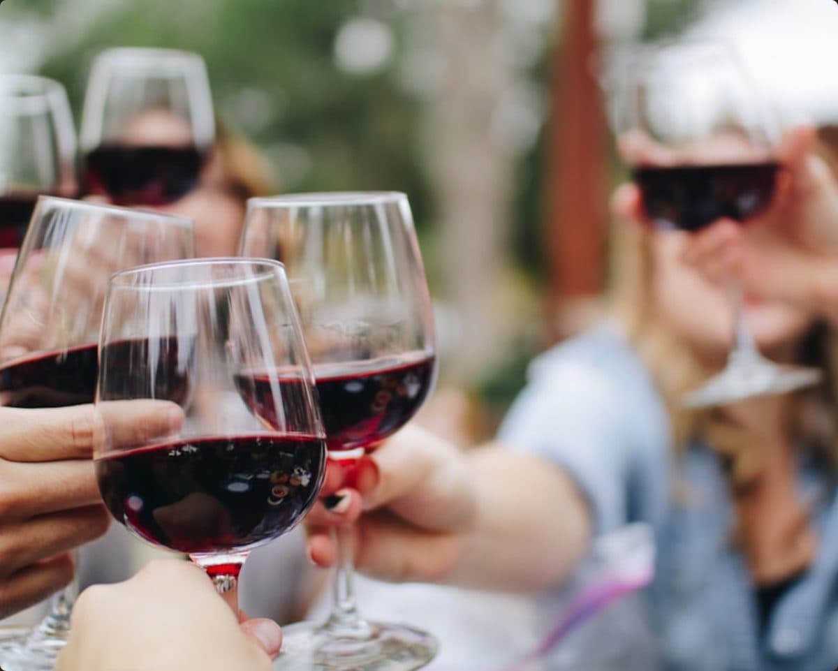 Des verres de vin levés autour d'une table, à l'heure de l'ardoise du sommelier