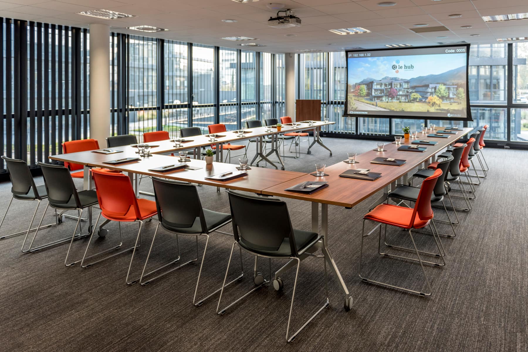 La salle de séminaire du Hub des Alpes en configuration en U, tables et chaises face à l'écran de projection